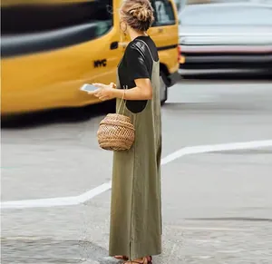 Side view of woman wearing loose olive green wide-leg jumpsuit and woven basket bag