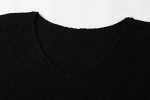 Macro dettaglio della maglia testurizzata e dello scollo a V di questo maglione nero da donna