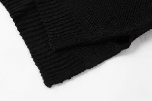 Dettaglio macro di un maglione lavorato a maglia nero con bordo a costine morbido.