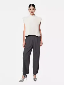 Full-body studio shot of a model wearing a chic white high-neck sleeveless knit vest