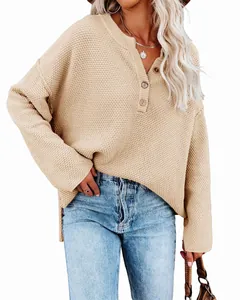 Close-up of casual loose beige knit sweater with wooden button half-placket detail.