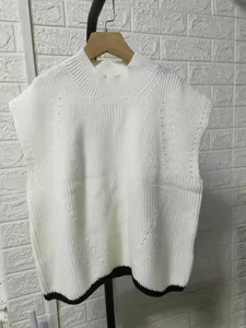 Close-up of white knitted mock neck sleeveless sweater vest with black hem