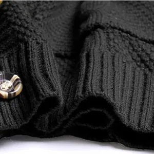 Close-up detail of black knitted cardigan showing ribbed hem and marble button