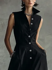 Detail view of a chic black sleeveless summer dress with a stand-up collar and buttons.