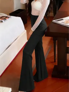 Vue détaillée d'un pantalon évasé noir à taille haute avec un drapé élégant dans une chambre.