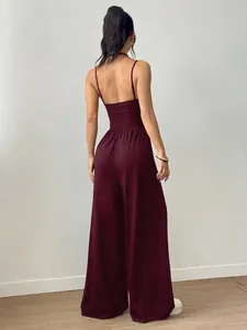Back view of a burgundy backless jumpsuit with wide legs and spaghetti straps.