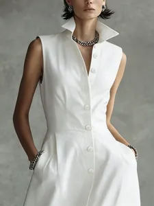 Detail of a white sleeveless dress with a stylish stand-up collar and buttons.