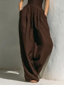 Detail view of dark brown wide-leg trousers with elegant high-waisted linen texture
