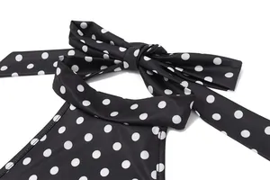 Close-up of black and white polka dot halter dress with elegant bow tie neckline detail