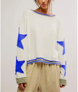 Détail du sweat à col rond ample avec des appliques d'étoiles bleues sur les manches.