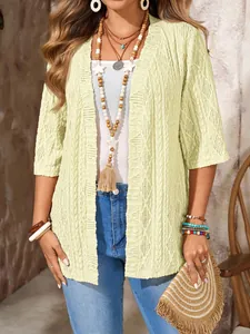 Detail eines bohème Häkel-Cardigans in blassgelbem Strick mit filigranem Lochmuster