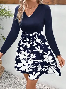 Detail of a navy V-neck long sleeve dress with white floral print skirt and tie waist.