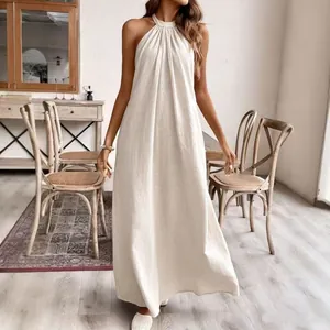 Model trägt ein lockeres beiges Halterneck-Maxikleid mit Leinentextur für den Sommerurlaub