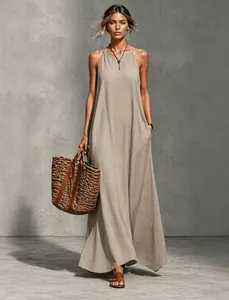 Full-length view of a khaki sleeveless halter maxi dress with a woven straw tote bag
