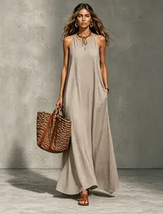 Detailed view of elegant sleeveless beige halter maxi dress with a summer straw bag
