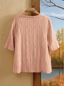 Rückansicht eines rosa Strickoberteils mit Lochmuster vor herbstlicher Kulisse.