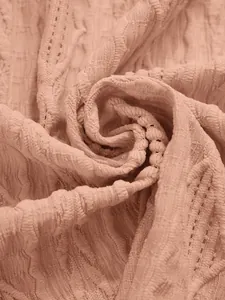Makro-Detail des weichen rosa Strickstoffs mit aufwendigen Durchbrüchen für Cardigan