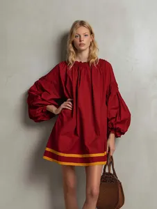 Model wearing a vibrant red oversized puff sleeve dress with yellow stripes at hem