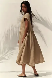 Abito estivo in cotone e lino presentato con luce naturale e ombre di foglie di palma