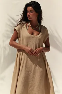 Primo piano di un abito lungo beige in cotone e lino con scollo a U e dettagli materici.