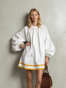 White puff sleeve baby doll dress with yellow striped hem detail for a vacation look.