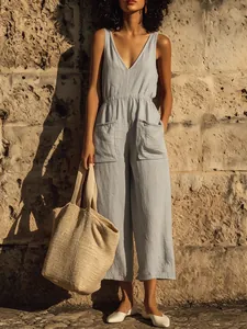 Detailed view of light blue linen V-neck jumpsuit with pockets in a summer setting
