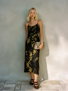 Κομψό μαύρο floral midi φόρεμα με ντεκολτέ σε στυλ ντραπέ σε απαλό φυσικό φωτισμό
