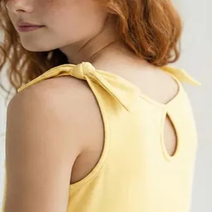 Close-up of yellow girls dress featuring adjustable shoulder ties and keyhole back