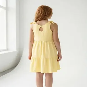 Back view of a yellow girl's summer dress with bow straps and a tiered skirt design.