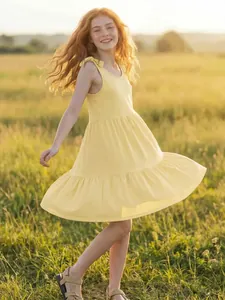 Girl's yellow sleeveless summer dress with shoulder ties in an outdoor sunny field