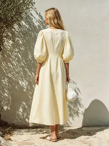 Back view of a pale yellow puff sleeve A-line midi dress with subtle textured fabric