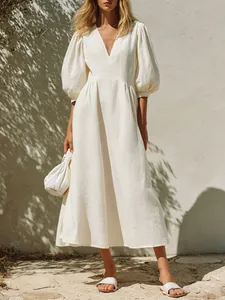 Full view of elegant white V-neck puff sleeve midi dress in a sunny vacation setting