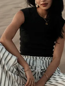 Close-up of a women's black sleeveless rib knit top styled with gold jewelry