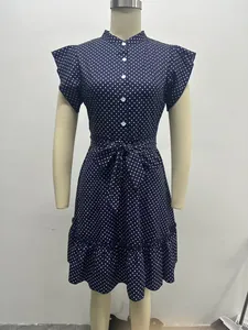 Front view of navy blue polka dot dress with ruffle sleeves and waist tie detail.