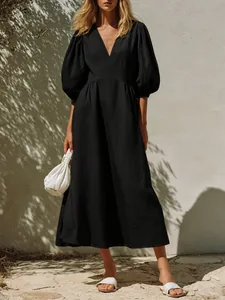 Elegant black V-neck midi dress with puff sleeves and cinched waist for a vacation look.