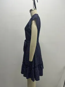 Side view detail of a navy blue polka dot dress with ruffle sleeves and tie waist styling