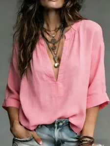 Detail of a casual pink V-neck blouse with a soft linen texture and layered necklaces