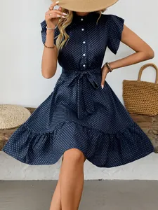Detailed shot of a navy blue polka dot summer dress with ruffled sleeves and waist tie