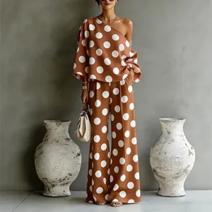 Elegante completo due pezzi con grandi pois bianchi su top monospalla marrone e pantaloni larghi