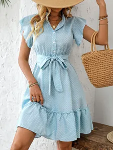 Detail view of light blue polka dot summer dress with ruffled sleeves and straw bag