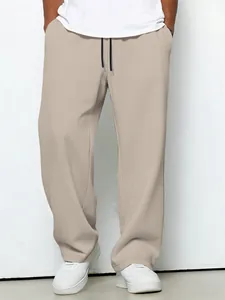 Detail shot of men's beige waffle knit straight-leg drawstring trousers in a casual style