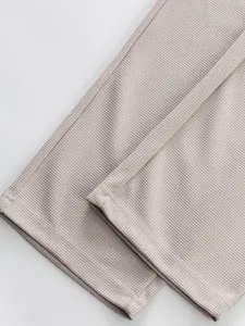 Detailed close-up showing the waffle texture and clean hem of beige casual pants.