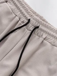 Close-up detail of beige waffle knit trousers waistband with black adjustable drawstring