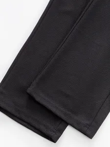 Detailed macro view of black waffle texture fabric hem on casual straight-leg pants