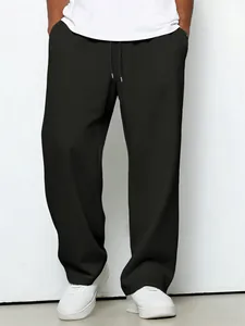 Detail view of men's black waffle textured straight leg casual drawstring trousers