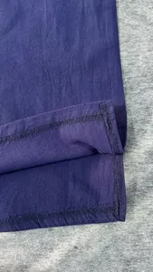 Dettaglio ravvicinato dell'orlo di una camicia in cotone lino blu navy e cuciture.