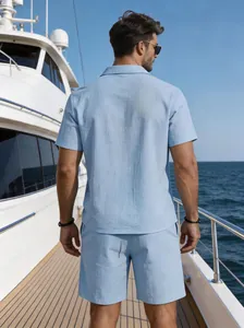 Back view of a man wearing a light blue linen shirt and shorts set on a luxury yacht deck