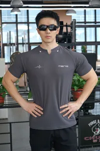 Vue détaillée d'un t-shirt de sport gris moulant porté par un modèle dans une salle de sport