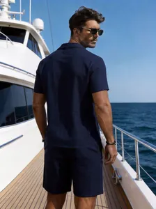 Back view of a man wearing a navy blue linen shirt and shorts set on a yacht deck