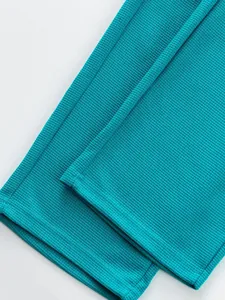 Close-up of teal ribbed fabric on casual straight-leg sports pants with clean hem detail